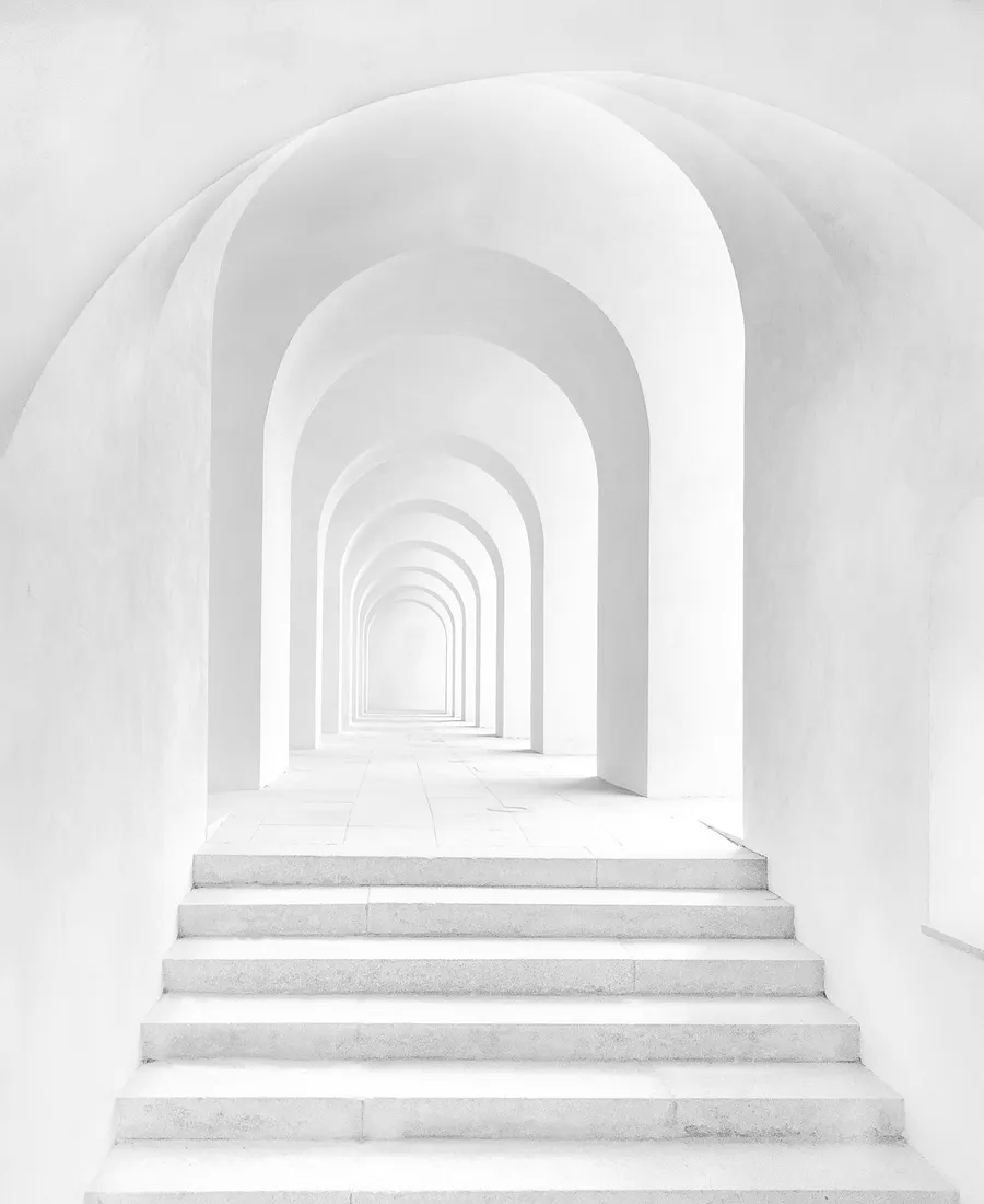 A minimalist white archway corridor with repeating arches and stairs, abstract architectural geometry in monochrome.